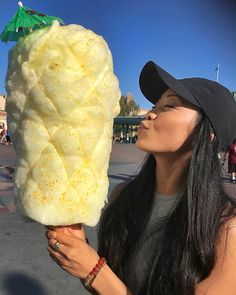 a woman holding up a giant piece of food to her face while wearing a hat