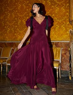 a woman in a purple dress standing next to a chair