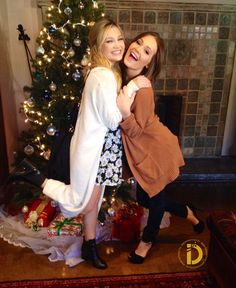 two women hugging in front of a christmas tree