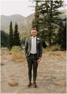 a man wearing a suit and tie standing in the dirt