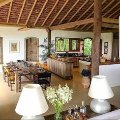 a large open kitchen and dining room area with wood beams on the ceiling, white table cloths in vases