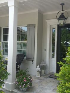 the front porch of a house with flowers and potted plants