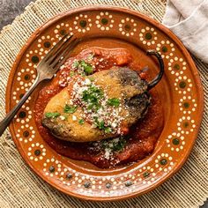 a brown plate topped with meat covered in sauce and garnished with parmesan cheese