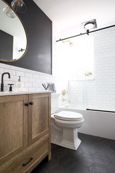 a white toilet sitting next to a wooden cabinet in a bathroom under a large mirror