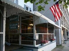 an american flag is hanging on the side of a building in front of a restaurant