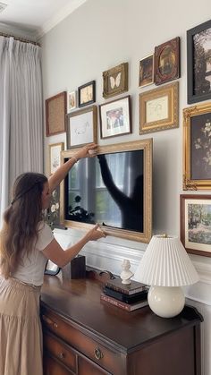 a woman standing in front of a tv with pictures on the wall