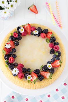 a white plate topped with a cake covered in berries and strawberries on top of it