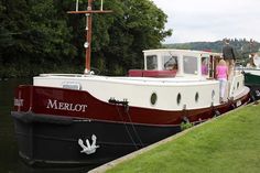 two people are standing on the deck of a boat docked at a dock with other boats in the water