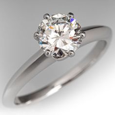 a white gold ring with a round brilliant cut diamond in the center, on a gray background