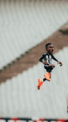 a soccer player jumping in the air with an orange shoe on his feet and mouth open