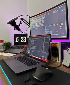 a laptop computer sitting on top of a wooden desk next to a monitor and keyboard