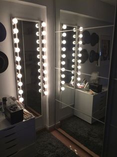 a mirror that has lights on it in a room with a dresser and other items