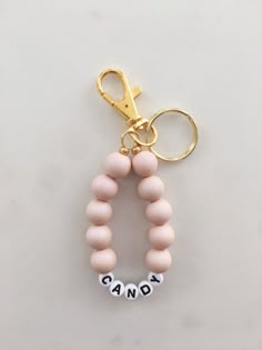 a pink beaded keychain with the word candy on it