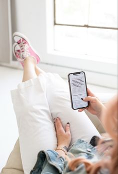 a person laying on a couch with their feet propped up and holding a cell phone