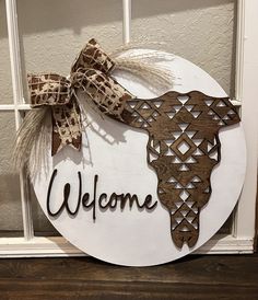 a welcome sign hanging on the side of a door with a cow's head