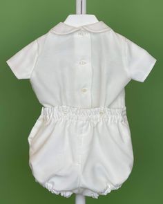 An elegant two-piece set for baby boys to wear during any special occasion. The top has a peter pan collar, handmade pleats, and short sleeves; it has buttons on the back for closure. The bottom is bubble-shorts with buttons on the sides for closure and an elastic band on the back. The interior, or lining, is made with cotton fabric, while the exterior is with off-white organza. Dry clean 2 piece set Interior: 100% cotton; exterior: 100% polyester Made in Spain Final Sale, no exchanges nor retur Classic Short Sleeve Sets For Baptism, Baptism Outfits For Boys, Toddler Baptism, Bubble Outfit, Bubble Clothes, Bubble Shorts, Outfits For Boys, Boy Baptism Outfit, Baptism Outfit