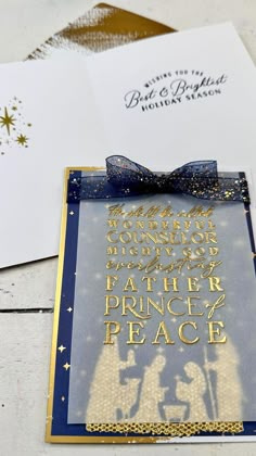 an envelope with a blue ribbon and gold foil on it, sitting next to some cards