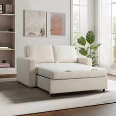 a white couch sitting on top of a wooden floor next to a book shelf filled with books