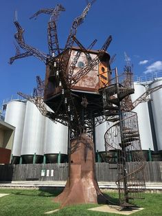 a tree house made out of metal spiral staircases in front of an industrial building