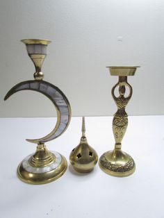 three antique brass candlesticks on a white table with a moon and crescent decoration