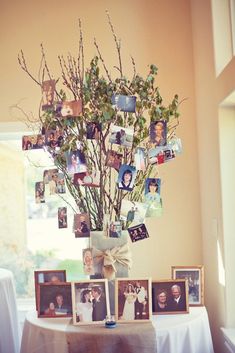 a vase filled with flowers and pictures on top of a table next to a window