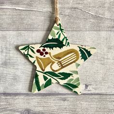 a christmas ornament hanging from a string on a wooden surface with leaves and music instruments