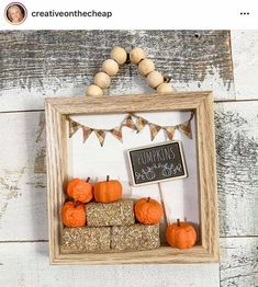 a wooden frame filled with pumpkins and marshmallows on top of a table