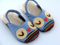 a pair of blue slippers with an owl design on the front and bottom, sitting on a white surface