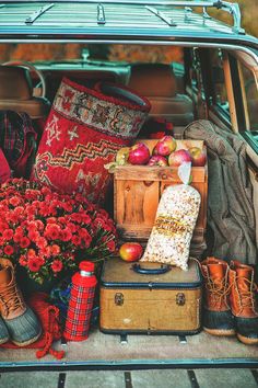 the trunk of an old car is filled with flowers and other items, including boots