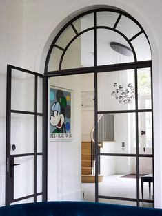 an arched glass door leading to a living room with mickey mouse artwork on the wall