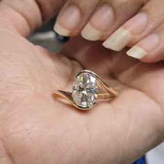 a woman's hand holding a ring with a large diamond in the middle of it