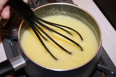 a person is stirring something in a pot on the stove with a whisk