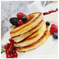 stack of pancakes with berries and raspberries on white plate