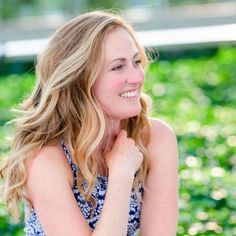 a woman with blonde hair is smiling and looking at the camera while wearing a blue dress