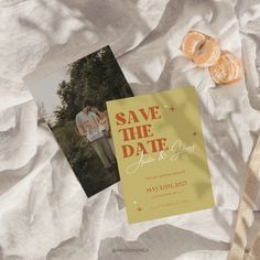 an orange slice next to a wedding save the date card on top of a bed