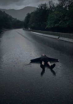 a person laying on the side of a wet road