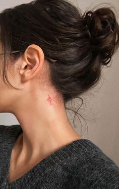 a woman with a small red star tattoo on her left side of her neck and behind her ear