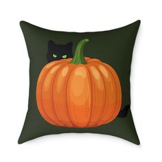 a black cat sitting on top of a green pillow with a pumpkin in the middle