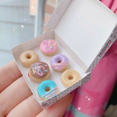 a hand holding a box with six donuts in it