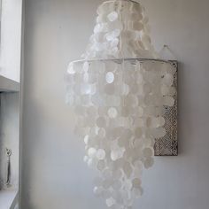 a white chandelier hanging from the side of a wall next to a shelf