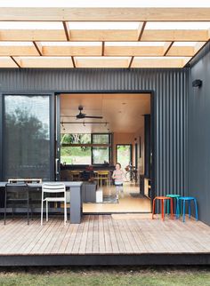 a person standing on a wooden deck in front of a house with sliding glass doors