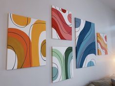 three abstract paintings hang on the wall above a couch