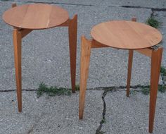 two wooden tables sitting on top of a cement ground next to each other, with grass growing between them