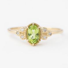 a ring with an oval shaped green stone surrounded by small white and yellow diamond accents