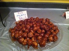 a glass plate filled with meatballs on top of a table next to two signs