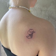 a woman's back with a small tattoo on her left shoulder and a cowboy hat