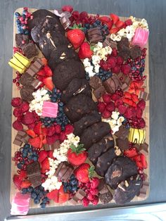 a cake covered in chocolate, strawberries and other toppings on top of a table