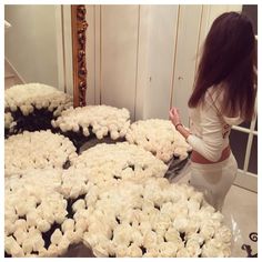 a woman kneeling down in front of a bunch of white flowers on a counter top