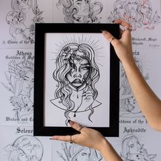 a woman is holding up a framed drawing