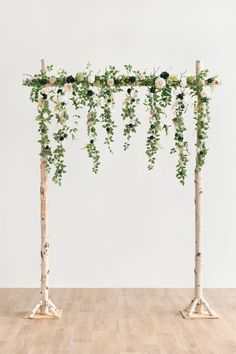 an arrangement of flowers and greenery is arranged on the top of two wooden poles